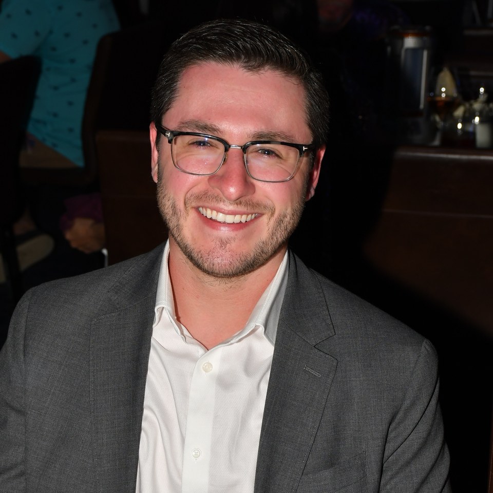 Kyle Evans smiling in a gray suit and white shirt.